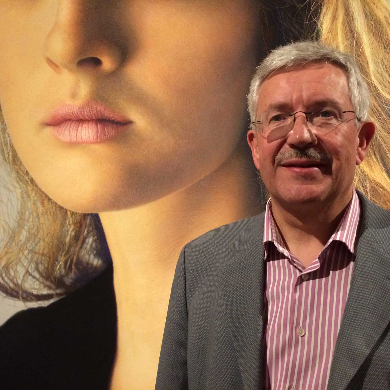A picture of a man standing in front of a large photograph of a woman