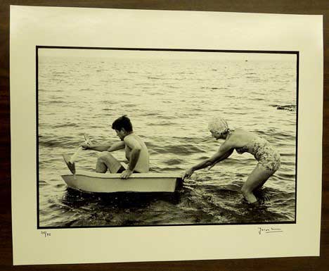 Black and white photograph of a woman pushing a man in a rowboat