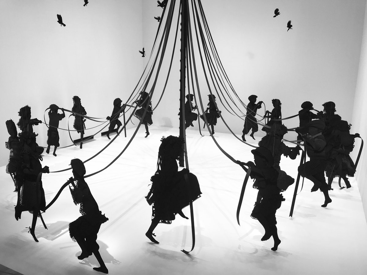 Silhouettes of children dancing around a maypole