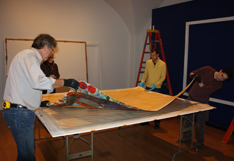 Museum staff lifting up Mequitta Ahuja's artwork