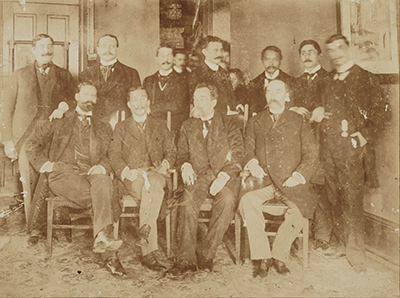 sepia toned photo of a group of men in formal dress
