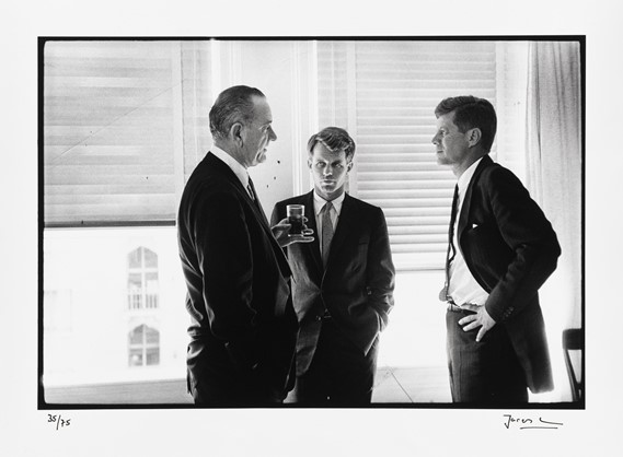 Black and white photo of three men standing in a circle and talking