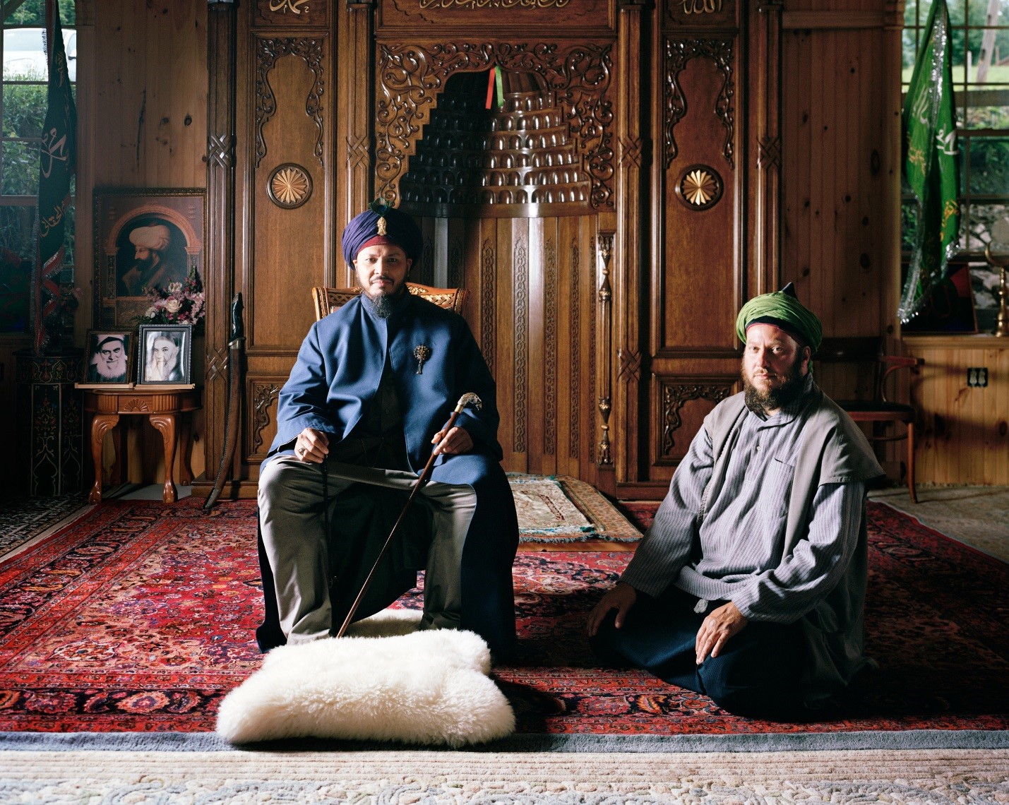 Two men, one sitting on floor, the other in chair