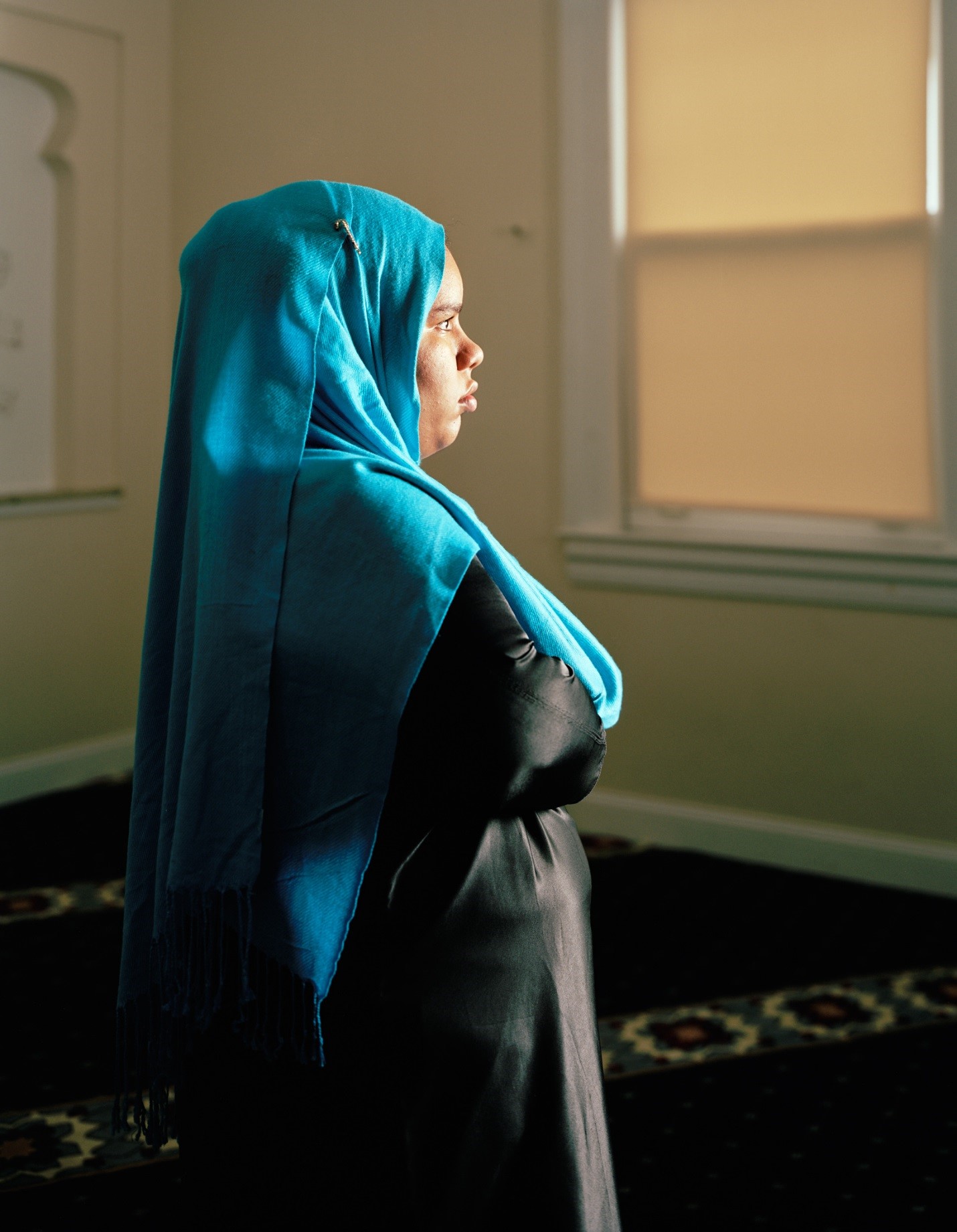 Woman in blue head scarf looking towards window