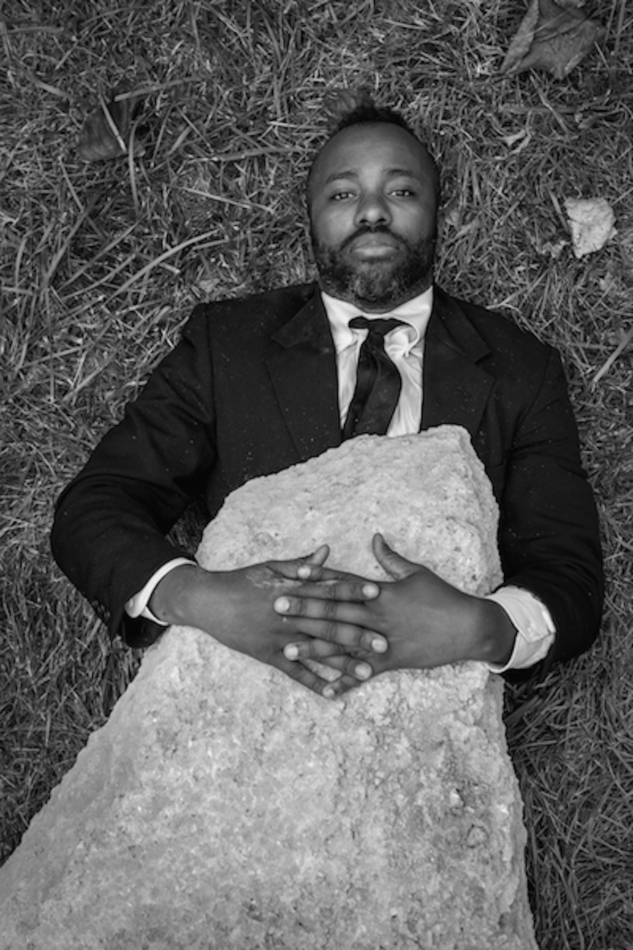 Black and white photo of a man buried under a rock and staring at the camera