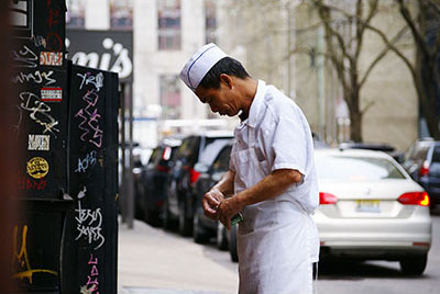 Asian man in an apron on the street in NYC