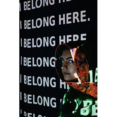 young woman in a headscarf standing in front of projected words