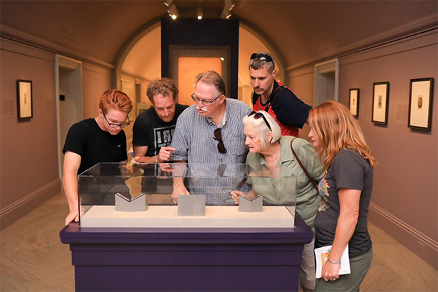 group of adults looking at collections in a case