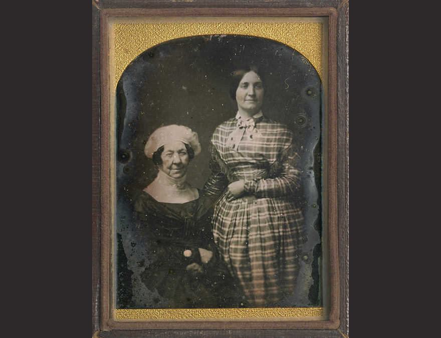 photograph of an older woman and a young woman standing behind her