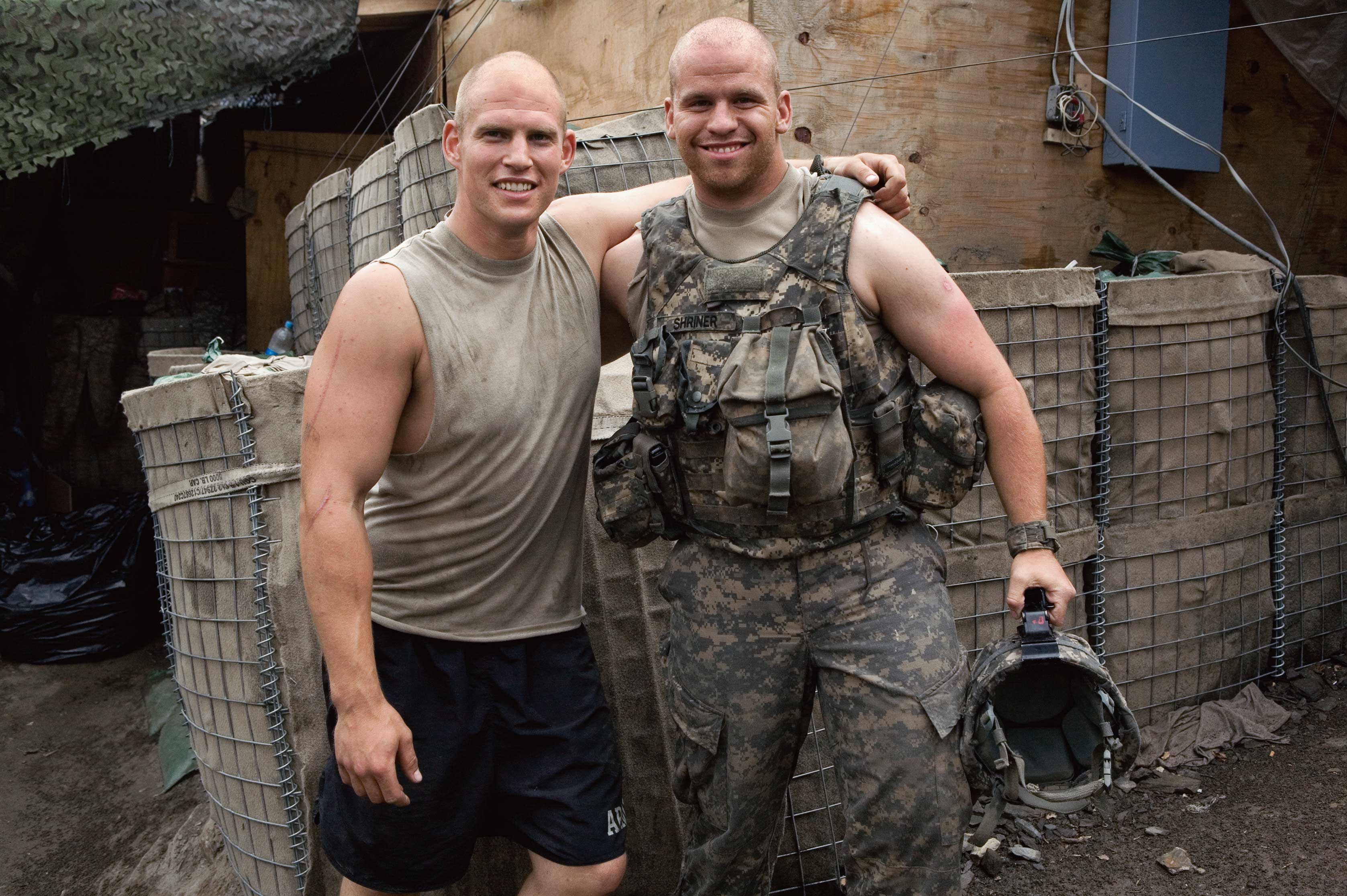 Photograph of two men with their arms around each other smiling at the camera