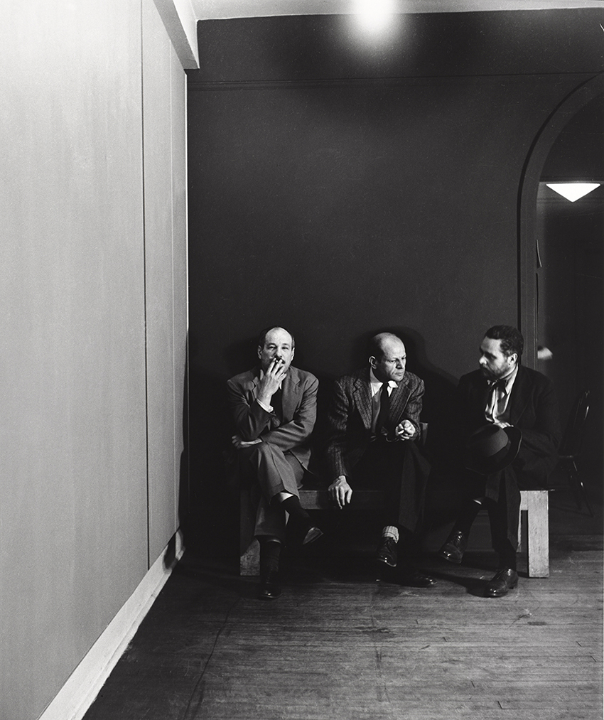 three men sitting together in a darkened room