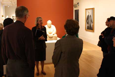 Wendy Wick Reaves at her talk, standing in front of Gertude Stein sculptur