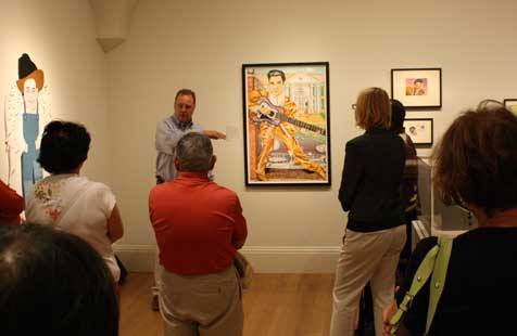 Warren Perry giving a talk and standing next to Red Groom's portrait of Elvis