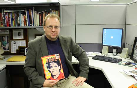 Warren Perry seated at his desk, with copy of Time magazine
