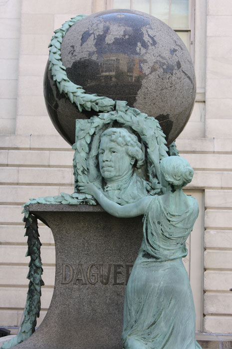 The Daguerre Monument -- a bust of Daguerre, topped by a large globe, and with a woman placing a wreath of leaves.  