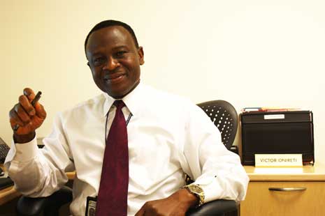 Victor Onireti at his desk, weaing white shirt and red tie