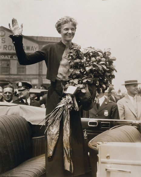 Blog_pop_quiz_earhart Amelia Earhart waving and holding a bouquet of flowers