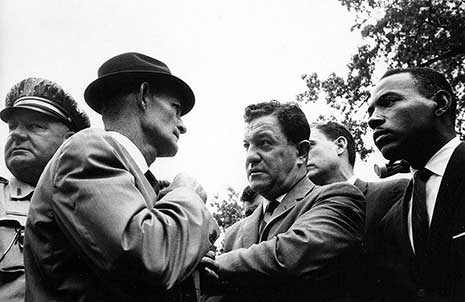 Black and white photo of James Meredith being escorted through tense group of men