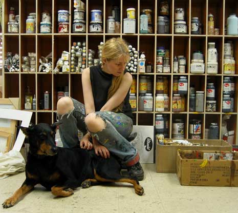 Tina Mion with a dog, seated in front of art supplies