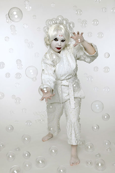 The artist in martial arts uniform gesturing, white background and bubbles in the air