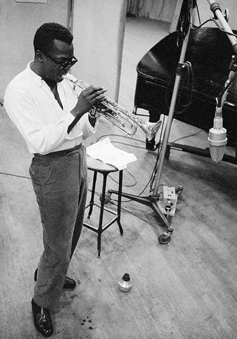 Blog_cool_miles_davis Black and white photo of Miles Davis on stage playing the trumpet, with sunglasses.
