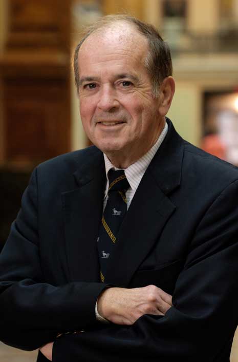 Color photo from the waist up of Martin Sullivan in a blue suit jacket and multi-color tie, standing inside the National Portrait Gallery.