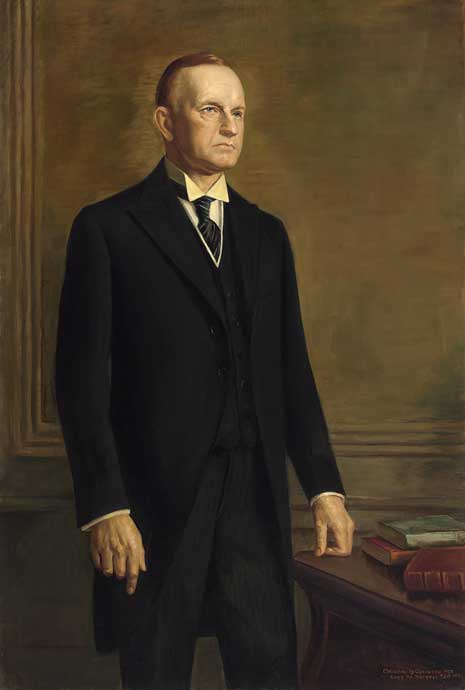 Painting from the knees up of Calvin Collidge wearing a dark suit, standing next to a desk with three books.