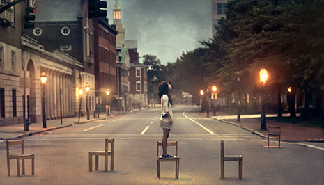 Teen Portrait of young woman in the middle of the street, standing on chair looking upwards