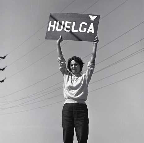 Blog_dolores_huerta_huelga Black and white photo of Dolores Huerta holding up sign reading "Huelga"