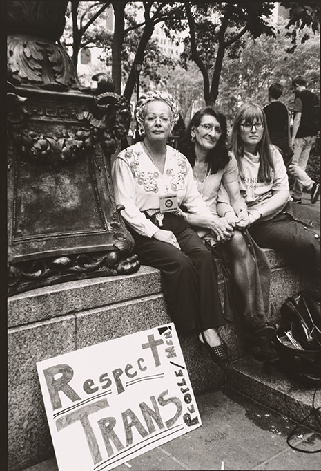 Black and white photo of Sylvia Rivera (with Christina Hayworth and Julia Murray) with sign reading "Respect Trans"