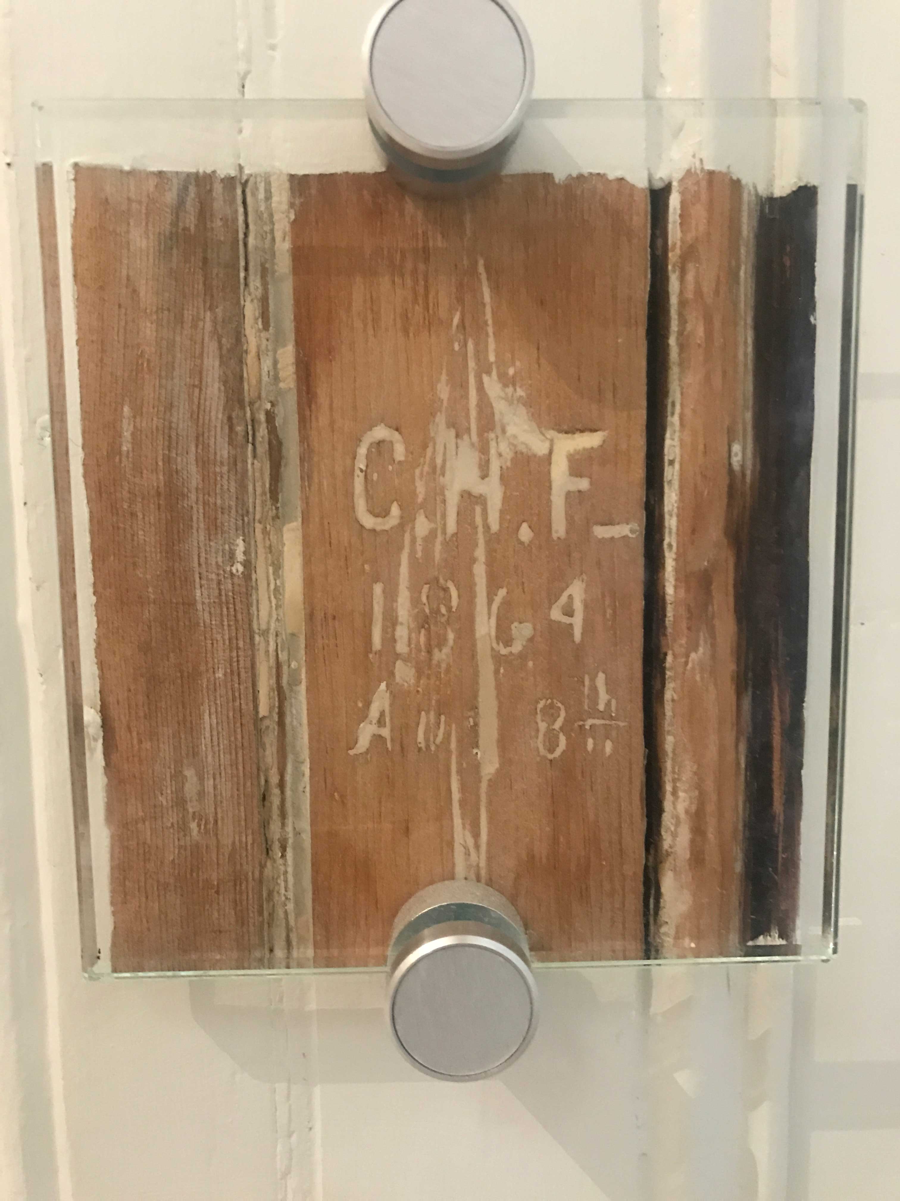 Photograph of initials and a date etched into wood