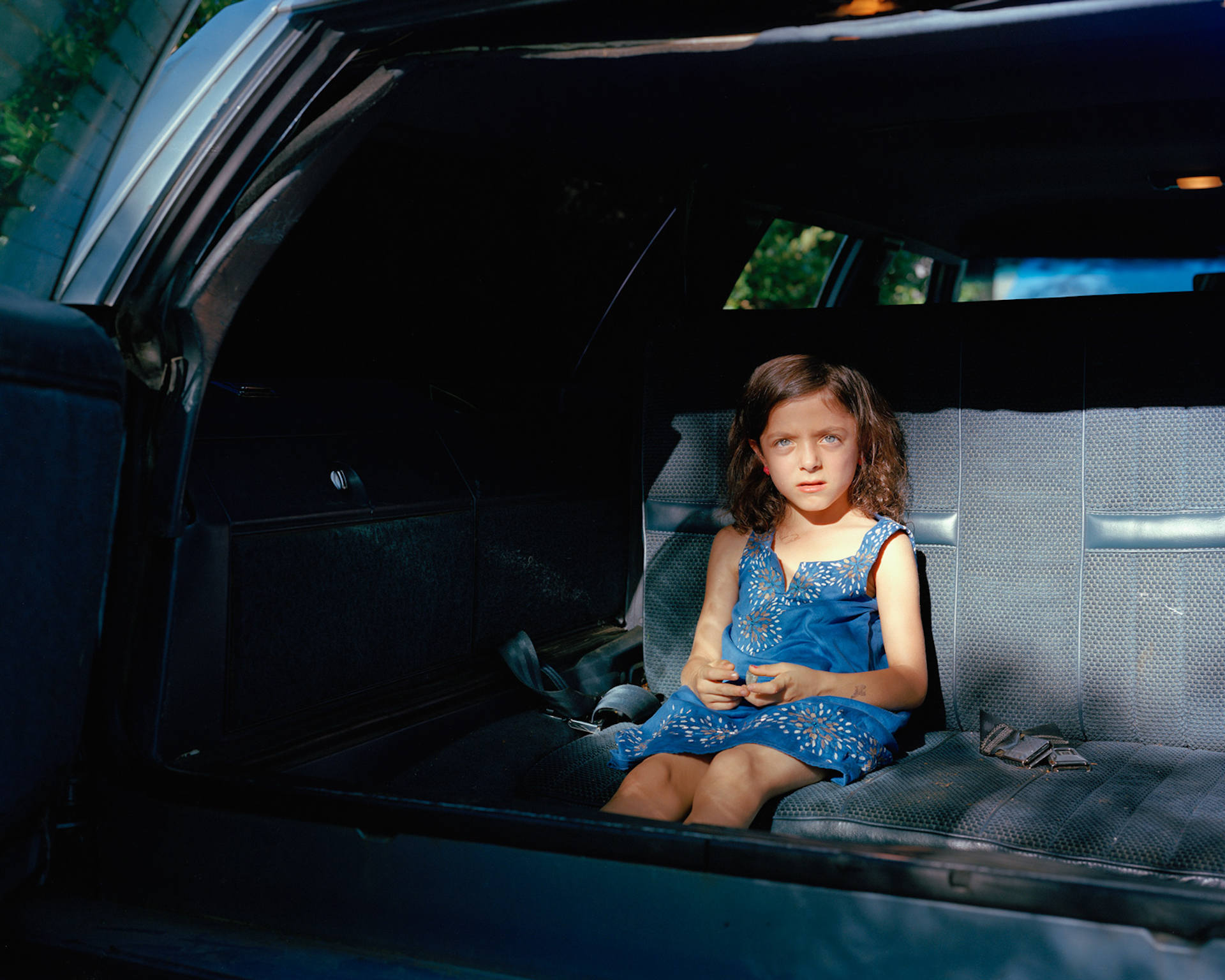 A small girl in the backseat of a car