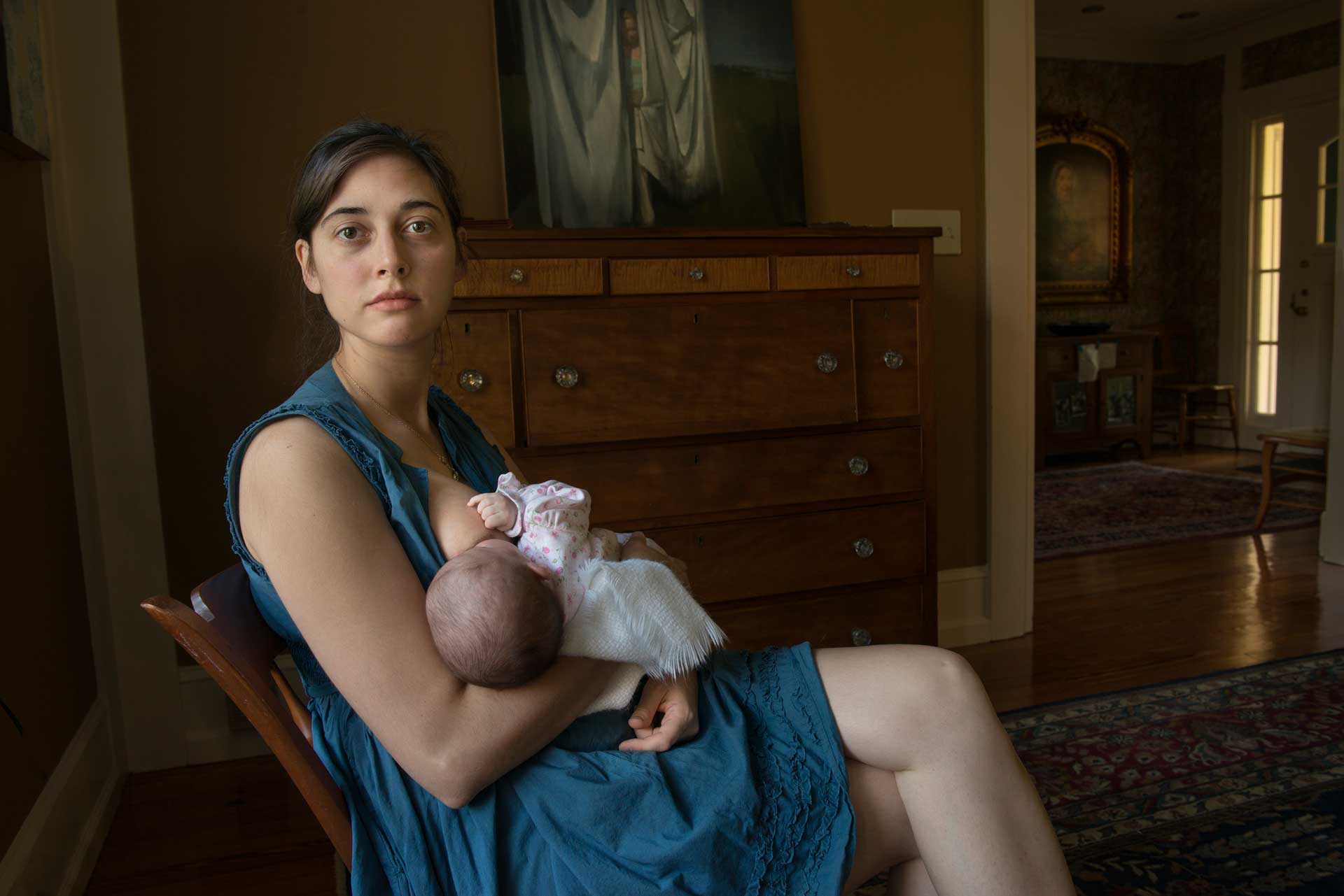 A woman wearing a dress breastfeeding her child