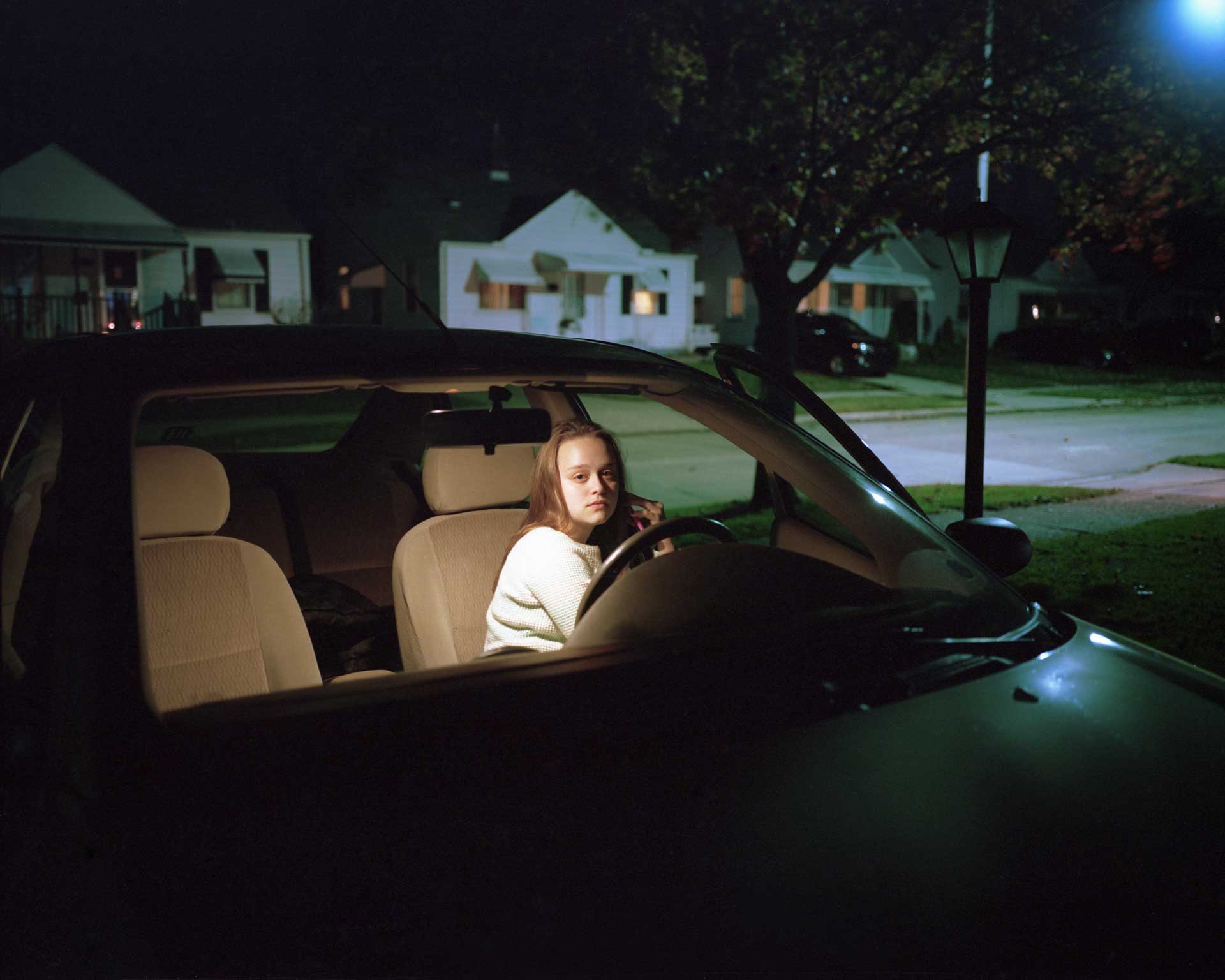 Young girl talking on her phone in the driver's seat of a car