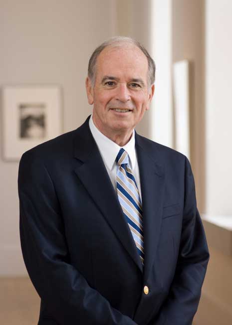 Color photo from the waist up of Martin Sullivan in a blue suit jacket and striped tie, standing inside the National Portrait Gallery.