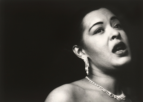 Blog_billie_holiday Black and white headshot photo of Billie Holiday, wearing earrings and a necklace.