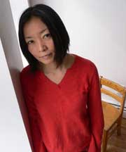 Color photo of Kumi Yamashita from the waist up, wearing a red shirt.