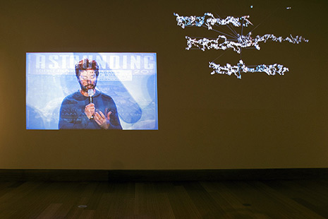 Projected image of person speaking, with word-like squiggles alongside