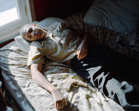 Photo of young man in ROTC uniform lying on bed