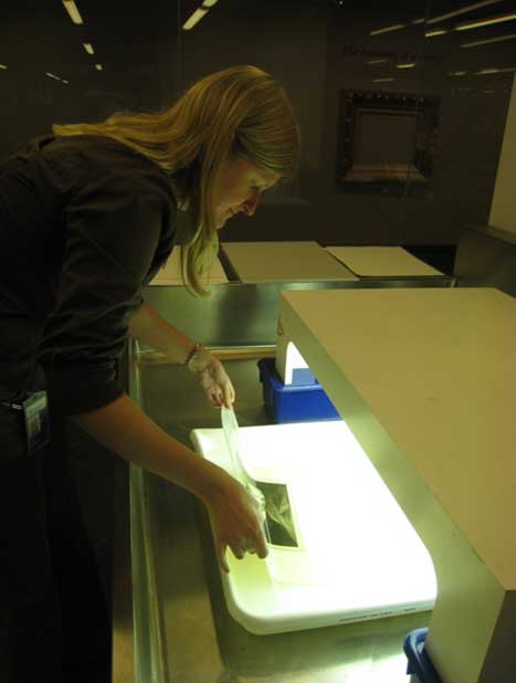 Conservator working with light bleaching bath, brightly lit
