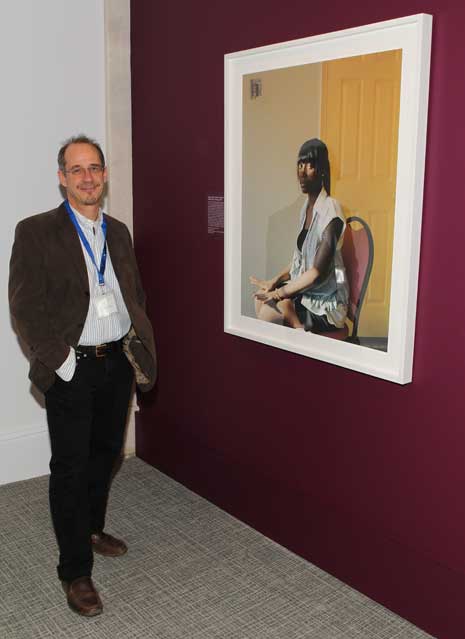 Paul D' Amato in the Portrait Competition exhibition, next to his portrait titled "Lillian"