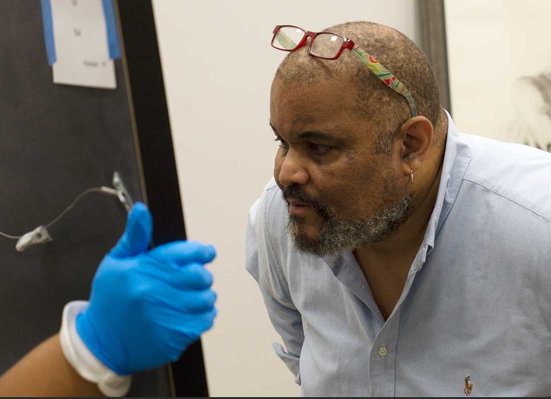 Juror Daewood Bey looking at an artwork.