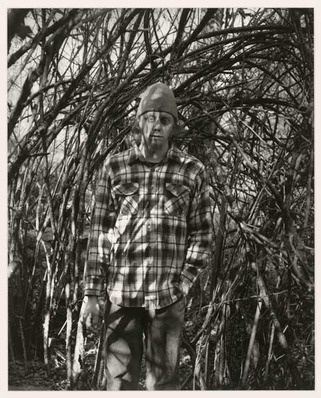 Black and white photo of man in plaid shirt in forest