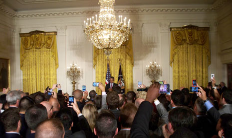 White House room with large chandelier and full of people