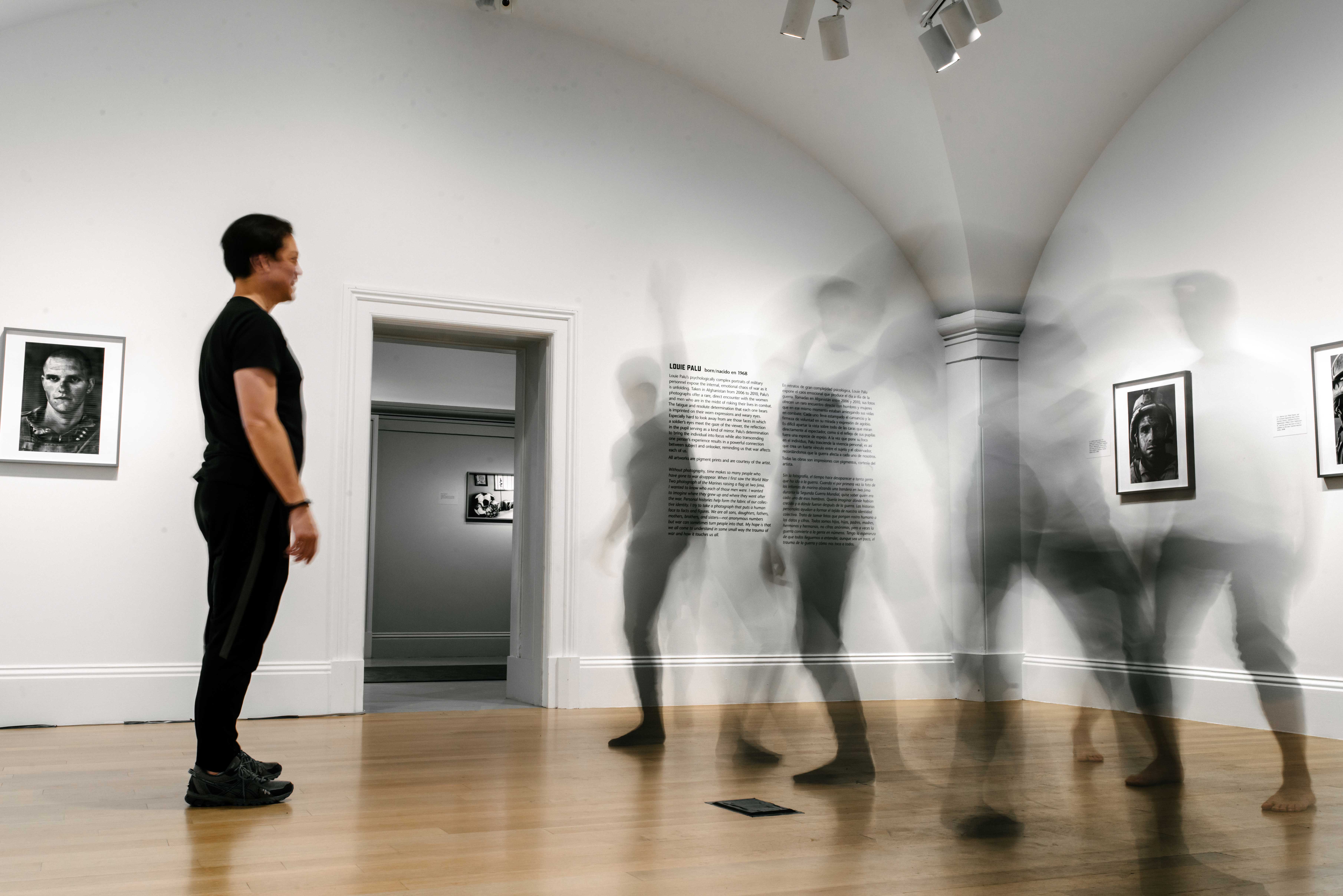 Image of a man standing in a gallery looking at three moving shapes