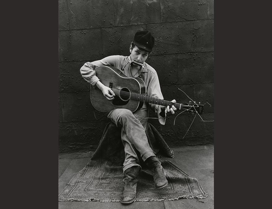 Photo of a seated man playing guitar