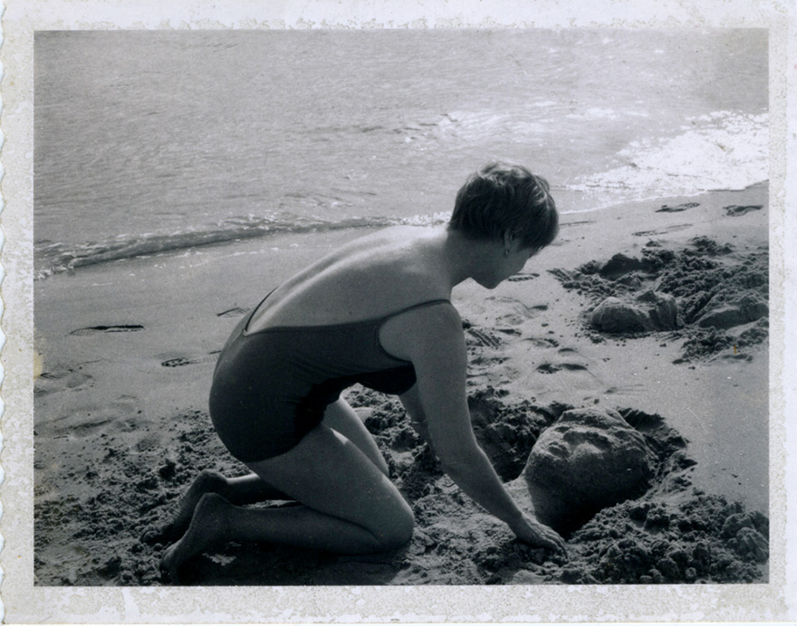 woman sculpting a portrait in the sand