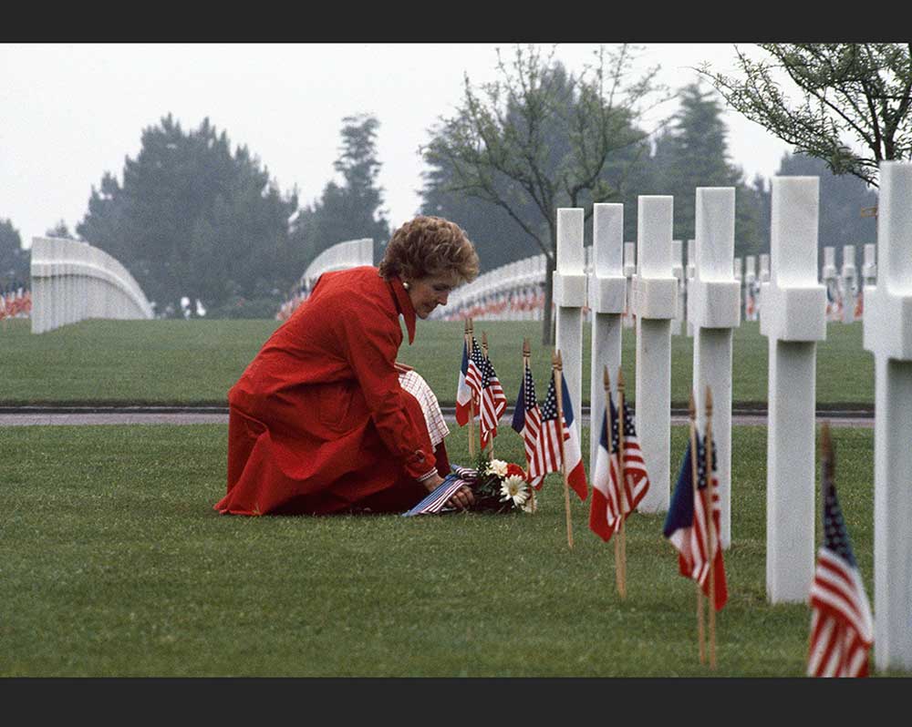 Woman placing flowers at a military gravesite