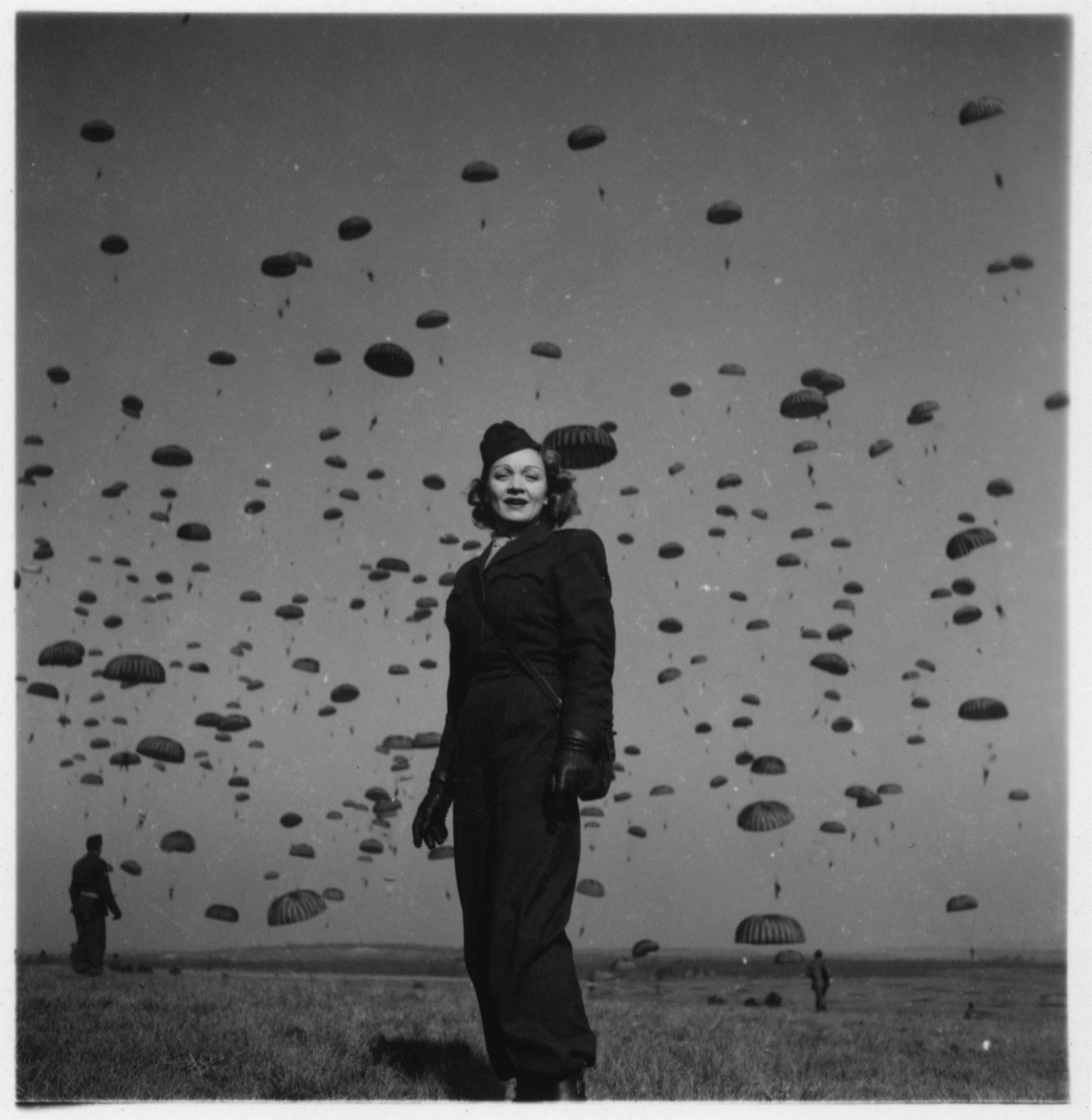 Black and white image of a woman in an army uniform with hundreds of paratroopers in the background