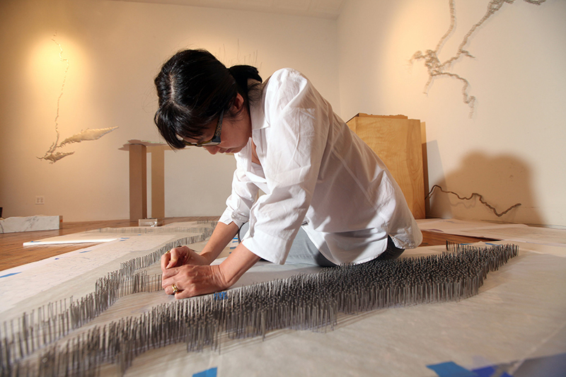 young woman working with pins on an architectural model